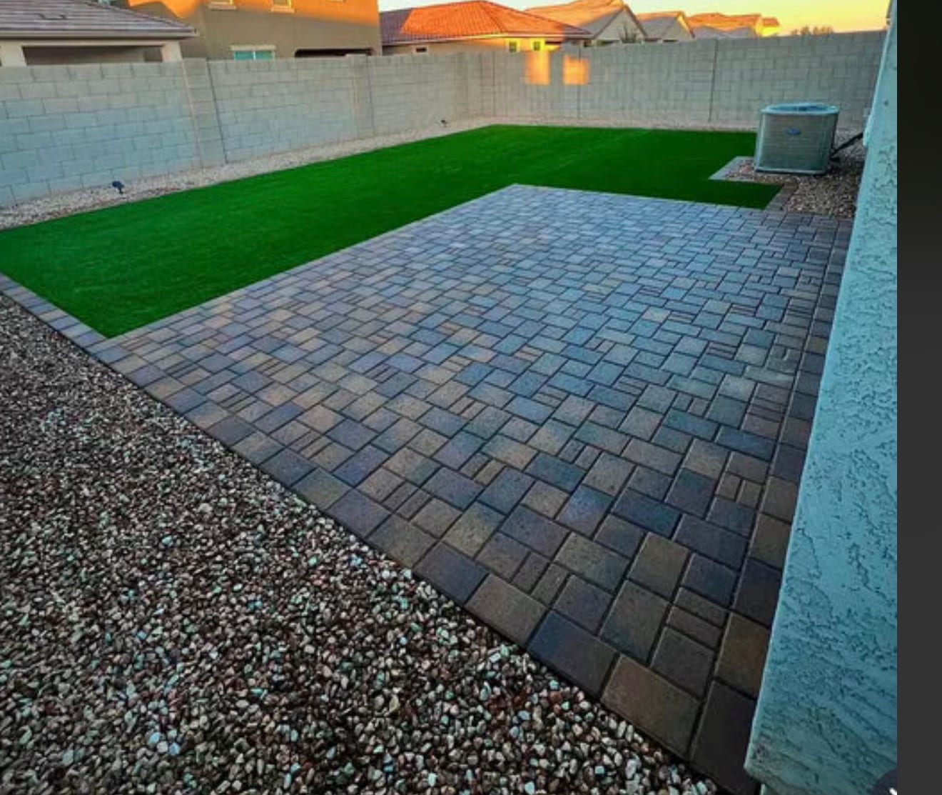 Paver patio with artificial turf and gravel borders at dusk in a Tucson backyard by Sorce Signature Outdoors