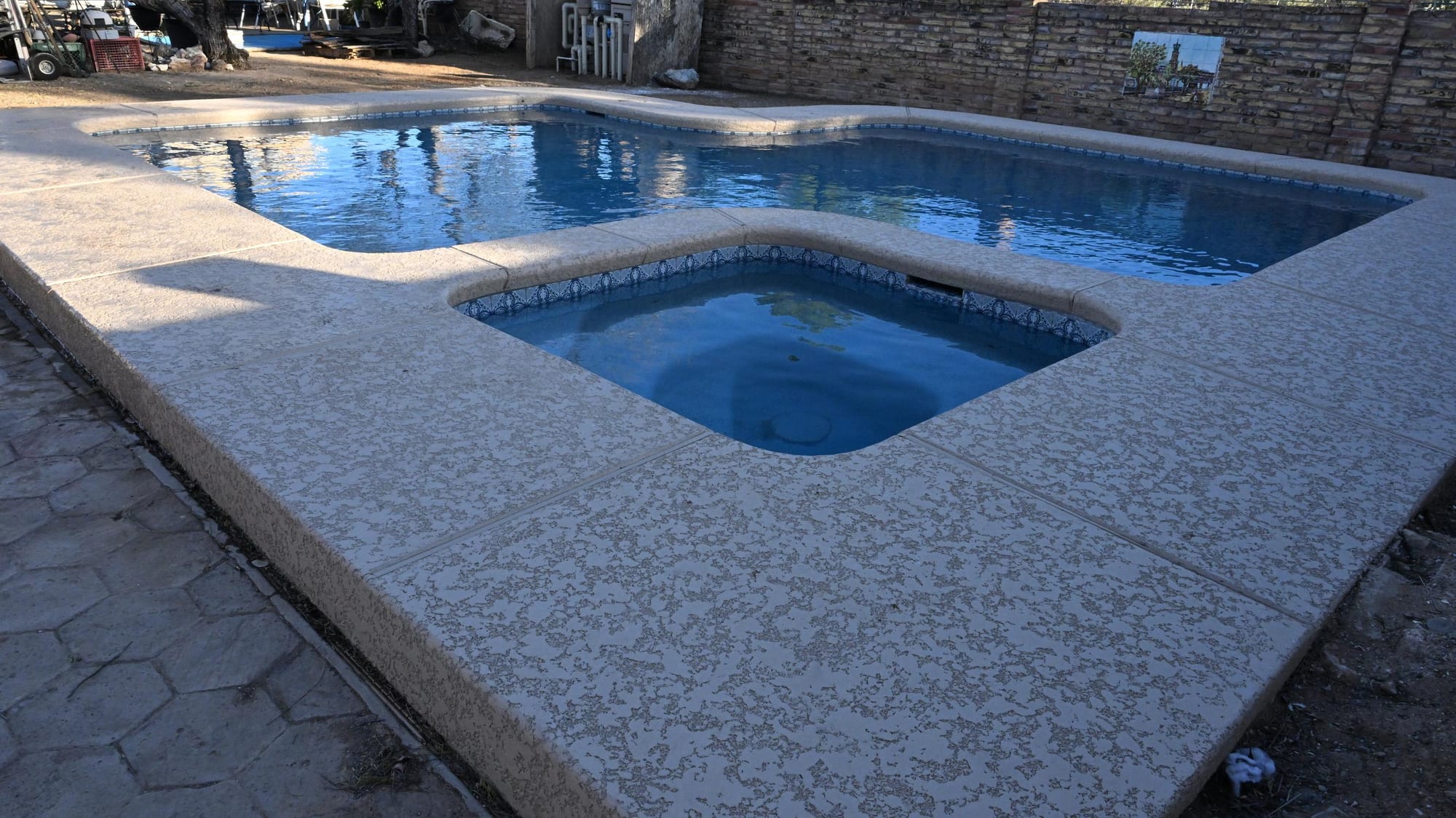 Custom backyard pool with a raised spa and stamped concrete decking in Tucson by Sorce Signature Outdoors